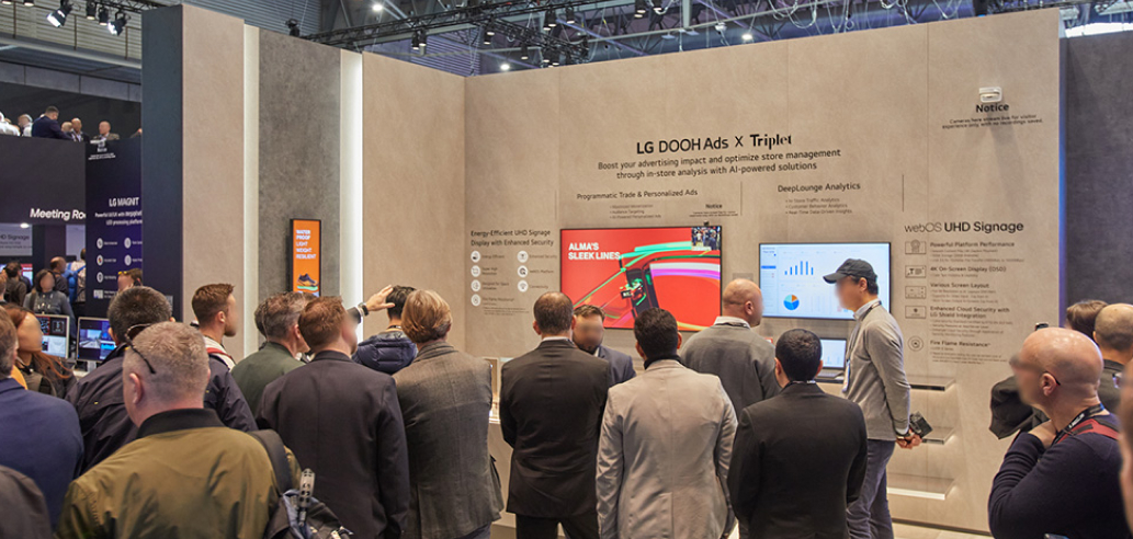 Attendees stand around a large display at LG ISE 2025, discussing and interacting with the innovative presentations.